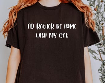 May include: Black t-shirt with white text that reads "I'd rather be home with my cat."