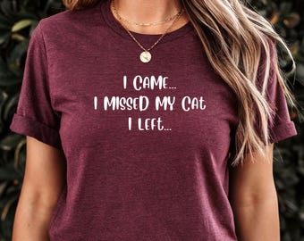 May include: A maroon t-shirt with the text "I came... I missed my cat I left..." printed in white.