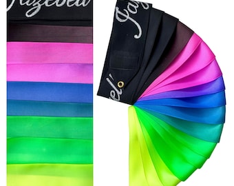 Op de afbeelding: Een set van 10 lintstroken in een regenboogkleurenpalet, waaronder zwart, bruin, roze, paars, blauw, teal, groen, limoengroen en geel. De linten zijn in een waaier vorm gerangschikt en zijn gelabeld met "Jazebell".