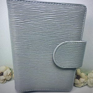 May include: A gray leather wallet with a textured surface and a flap closure.
