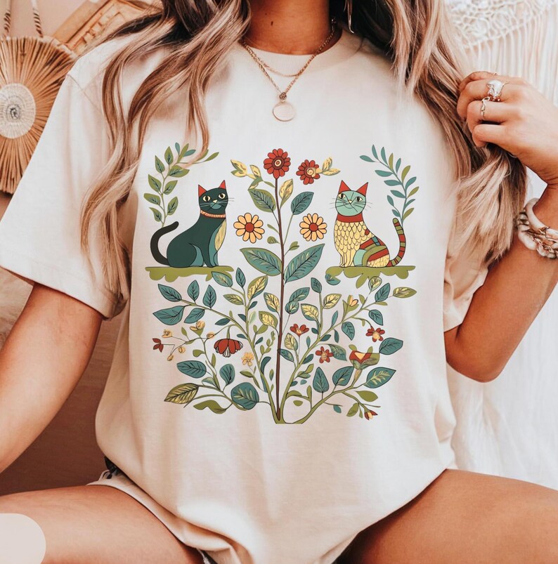 A Cottagecore-inspired shirt featuring whimsical cats and vintage floral patterns, perfect for cat lovers and nature enthusiasts