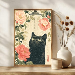 May include: A framed art print featuring a black cat under a shower, surrounded by pink peonies and green foliage. The cat looks upwards with water droplets on its fur. The artwork has a vintage, Japanese-inspired aesthetic.
