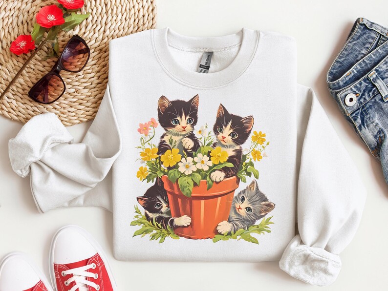 A retro-inspired t-shirt featuring an adorable kitten in a whimsical garden setting with vibrant flowers and vintage-style accents. Perfect for cat lovers and fans of nostalgic, playful designs.