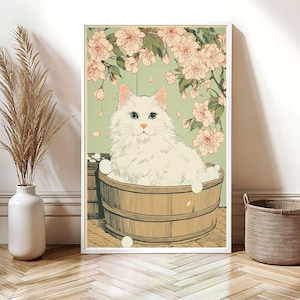 May include: A framed art print featuring a white cat in a wooden tub, surrounded by bubbles. The background is a light green with pink cherry blossoms. The cat has blue eyes and fluffy white fur.