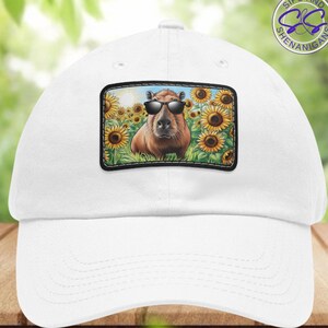 May include: White baseball cap with a patch featuring a capybara wearing sunglasses in a field of sunflowers. The patch has the text "Sips and Shenanigans" on it.