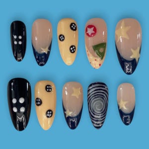 Könnte beinhalten: Ein Set aus zehn künstlichen Nägeln in verschiedenen Designs. Die Nägel weisen eine Mischung aus Farben auf, darunter Schwarz, Beige, Gelb und Marineblau. Einige Nägel haben Stern-, Knopf- und Wirbelmuster. Die Nägel werden auf hellblauem Hintergrund präsentiert.