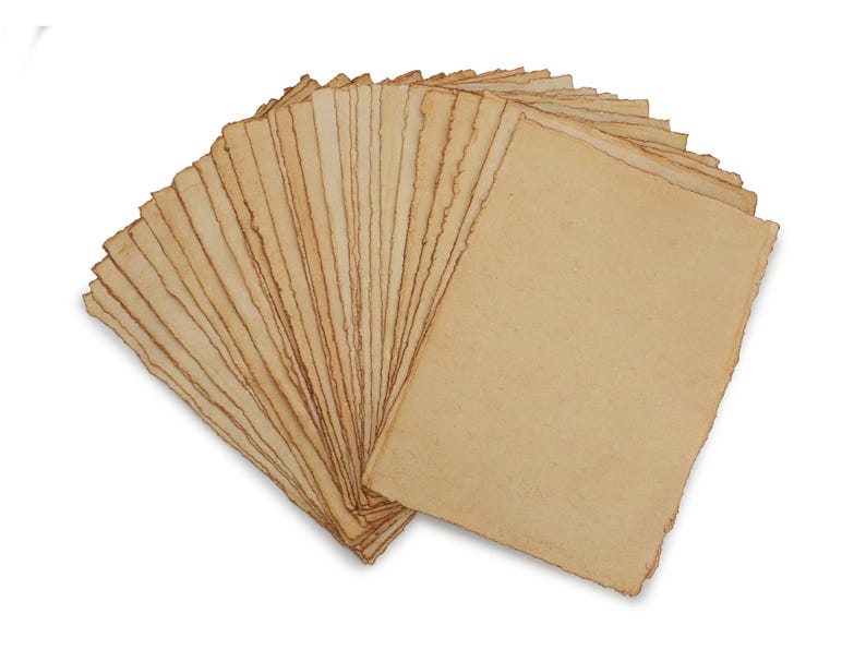 Op de afbeelding: Een stapel handgemaakte papieren vellen met gescheurde randen, uitgespreid tegen een witte achtergrond. Het papier heeft een warme, beige tint en de randen zijn iets donkerder, wat het een verouderde uitstraling geeft. Ideaal voor kunstprojecten.