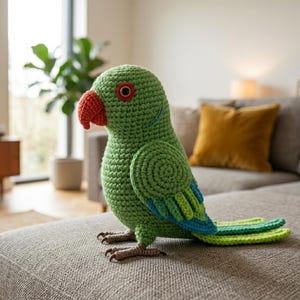 May include: A crocheted parrot toy featuring a bright green body, a textured orange beak, and a dark eye with a red ring. The wings and tail display layered shades of blue and light green yarn, while the feet are crafted in brown yarn.