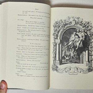 May include: Open book with text and a black and white illustration. The left page has printed text, while the right page features a detailed drawing of figures in an arched setting. The book has a green cover with a patterned design.