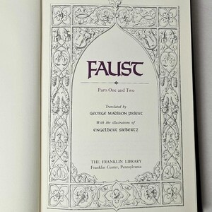 May include: Open book with the title page of "Faust" by Johann Wolfgang von Goethe. The title is in a decorative arch, with the text "Parts One and Two" below. The book is from The Franklin Library.