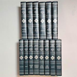May include: A collection of hardcover books with dark blue covers. The spines feature white text and decorative diamond patterns. The books are arranged in two stacks, showcasing a classic literary collection.