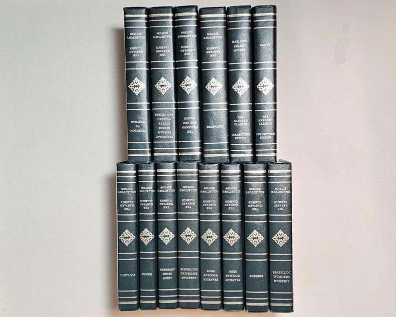 May include: A collection of hardcover books with dark blue covers. The spines feature white text and decorative diamond patterns. The books are arranged in two stacks, showcasing a classic literary collection.