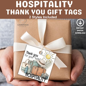 May include: A wrapped gift with a white ribbon and a tag that says "Thank you for your suite." The tag features illustrations of luggage, a sun, and the word "HOSPITALITY."