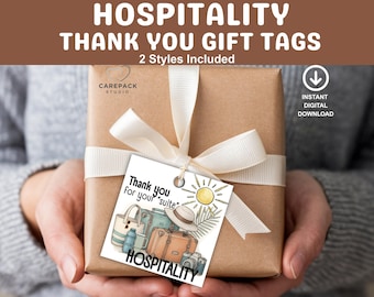 May include: A wrapped gift with a white ribbon and a tag that says "Thank you for your suite." The tag features illustrations of luggage, a sun, and the word "HOSPITALITY."