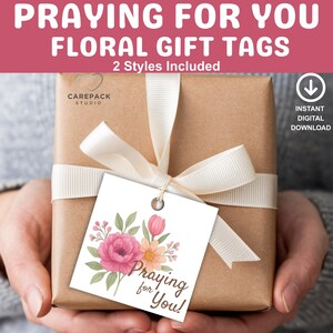 Puede incluir: Un regalo envuelto con una cinta blanca y una etiqueta floral. La etiqueta presenta un diseño de acuarela de flores rosas y naranjas con el texto "Praying for You!". La imagen también incluye el texto "Floral Gift Tags" y "Instant Digital Download."