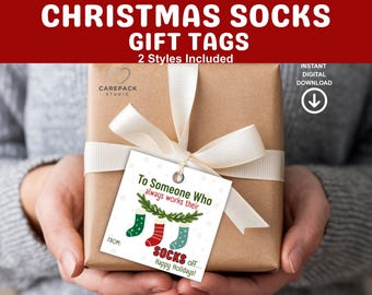 Könnte beinhalten: Ein Geschenk mit weißem Band und einem Geschenkanhänger mit der Aufschrift "To Someone Who always works their SOCKS off... Happy Holidays!". Der Anhänger zeigt drei Weihnachtsstrümpfe. Der Text "CHRISTMAS SOCKS GIFT TAGS" steht oben.