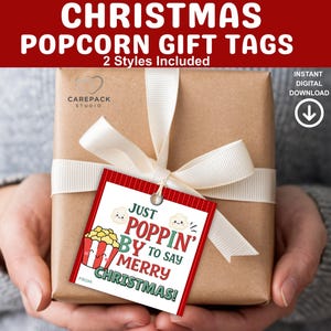 May include: A wrapped gift with a white ribbon and a popcorn-themed Christmas gift tag. The tag reads "Just Poppin' By to Say Merry Christmas!" in red, white, and green. The image also includes the text "CHRISTMAS POPCORN GIFT TAGS".