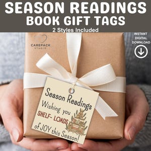 Puede incluir: Un regalo envuelto con una cinta color crema y una etiqueta de regalo. La etiqueta dice "Season Readings" y "Wishing you SHELF-LOADS of JOY this Season!" El regalo es sostenido por una persona.