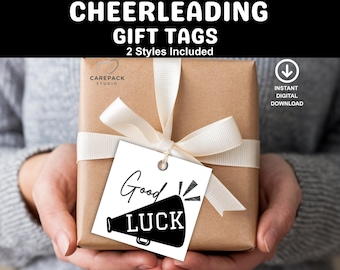 May include: A wrapped gift box with a white ribbon and a tag that says "Good Luck" with a megaphone graphic. The gift box is wrapped in brown paper and the tag is white with black text. The image includes the text "CHEERLEADING GIFT TAGS".