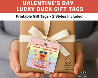 May include: A wrapped gift with a cream ribbon and a Valentine's Day gift tag. The tag features a cartoon duck wearing sunglasses and holding a sign that says "Happy Valentine's Day". Text on the tag reads "I am One Lucky Duck to have a friend like you."
