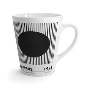 Puede incluir: Un juego de tres tazas de cerámica con acabado mate moteado. Las tazas son de color crema, gris claro y gris oscuro. Cada taza tiene un diseño simple y minimalista con un asa redondeada. Para café o té.