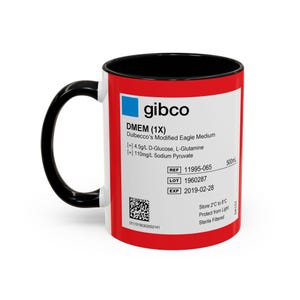 May include: A white ceramic mug with a black handle and interior. The mug features a red band with the text "gibco DMEM (1X)" and other scientific information. The mug is designed to hold approximately 500ml.