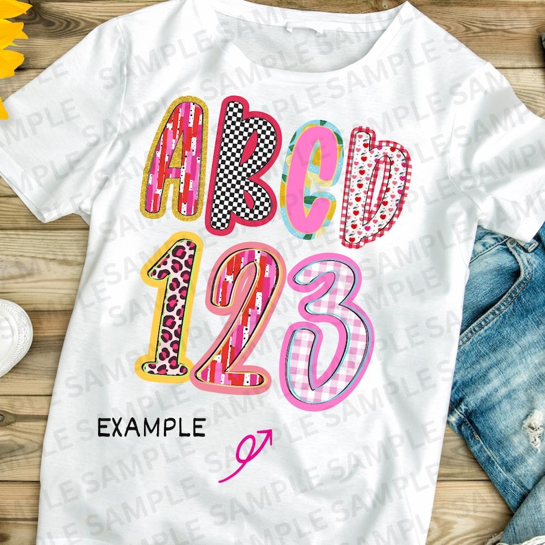 May include: White t-shirt featuring the letters "ABCD" and numbers "123" in vibrant patterns. Designs include leopard print, hearts, and a checkered pattern. The word "EXAMPLE" is printed below the numbers, showcasing a playful design.