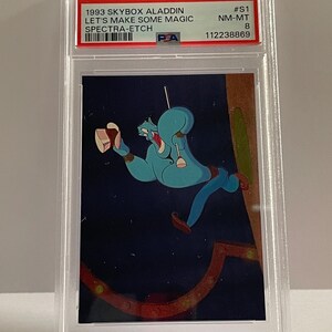 May include: A graded trading card featuring the Genie from Disney's Aladdin. The card is from the 1993 Skybox Aladdin series, with the text "LET'S MAKE SOME MAGIC SPECTRA-ETCH". The Genie is depicted in a dynamic pose against a dark blue background.
