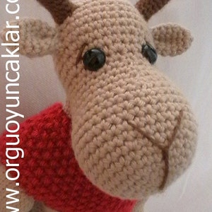 May include: A crocheted reindeer toy with brown antlers, a red scarf, and black eyes.