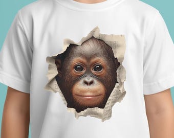 May include: White t-shirt with a detailed illustration of an orangutan's face emerging from a torn paper effect. The orangutan has brown fur and a gentle expression. The torn paper reveals printed text.