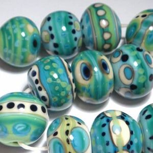 May include: A collection of ten turquoise and white glass beads with various patterns. The beads are round and have a glossy finish.