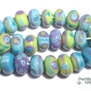 May include: A collection of 20 colorful glass beads with swirls of blue, green, and purple. The beads are all different shapes and sizes, and they are strung together on a white string.