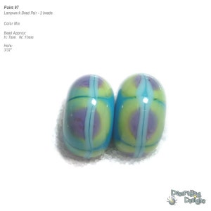 May include: A pair of lampwork glass beads with a blue, yellow, and purple color scheme. The beads are approximately 7mm high and 11mm wide. The hole size is 3/32 inches.