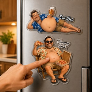 May include: Two decorative refrigerator magnets featuring cartoon-style men with exposed bellies. The top magnet shows a man holding a beer with the text Dad Bob. The bottom magnet shows a man sitting in a chair eating pizza with the text Hungry Dad.