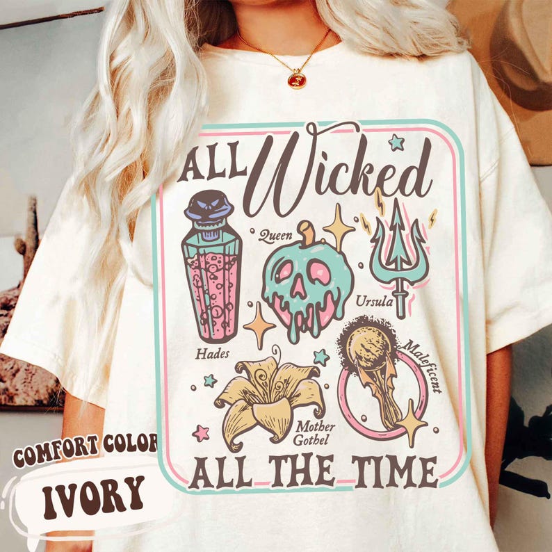 May include: Ivory-colored t-shirt with a graphic design featuring the text "ALL Wicked ALL THE TIME." The design includes illustrations of a poison bottle, a skull, a trident, a flower, and a magic mirror. The shirt is labeled "COMFORT COLOR."