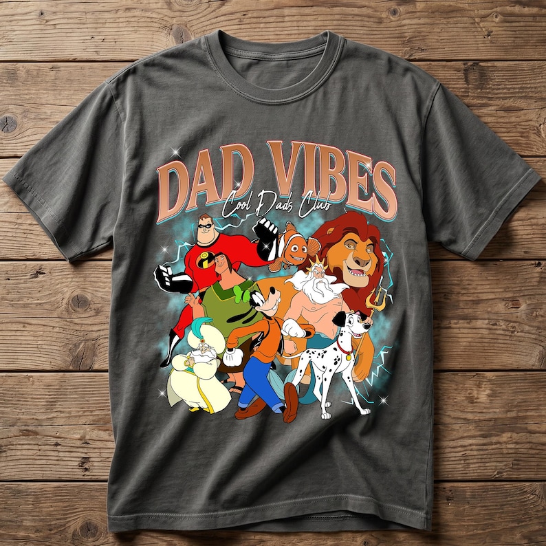 Puede incluir: Camiseta gris con un gr&aacute;fico de personajes de dibujos animados y el texto "DAD VIBES Cool Dads Club". El dise&ntilde;o incluye personajes como Mr. Incre&iacute;ble, Simba y Goofy. La camiseta est&aacute; hecha de un material suave.