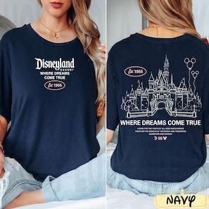 May include: Navy blue t-shirt with white Disneyland Resort text and the phrase "Where Dreams Come True." The back features a castle graphic and the text "Where Dreams Come True" with "Est. 1955."