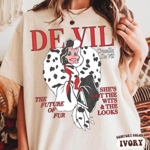 May include: A white ceramic mug with a black handle and the text "But First, Coffee" in a bold, black font. The mug is set against a blurred background, suggesting a cozy setting.