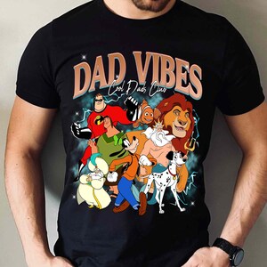 Puede incluir: Camiseta negra con un gr&aacute;fico de personajes de dibujos animados, incluyendo Los Incre&iacute;bles, Nemo, Simba y otros. El texto "DAD VIBES Cool Dads Club" est&aacute; impreso sobre los personajes en un estilo retro.