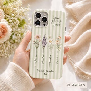 May include: A light green and white striped phone case featuring four illustrated wildflower stems, each labeled with the names Olivia, Amelia, Sophia, and Harper. The text Love grows here and Mama's Garden is printed on the case with a small bow icon.