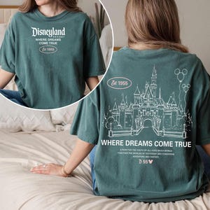 May include: Teal-colored t-shirt with "Disneyland Resort" and "Where Dreams Come True" printed in white. The back features a castle graphic and the text "Where Dreams Come True". Est. 1955.