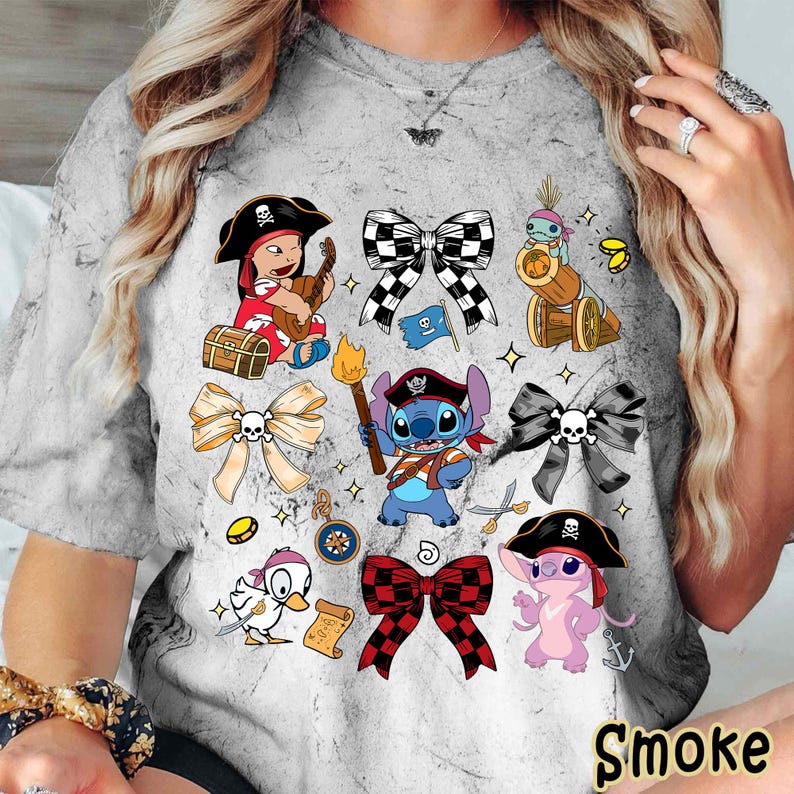 Może przedstawiać: Szara koszulka typu tie-dye z postaciami pirat&oacute;w z kresk&oacute;wek i kokardkami. Projekt zawiera pirackie dziecko grające na gitarze, Stitcha z pochodnią i r&oacute;żowego pirata-kosmitę. Słowo "Smoke" jest wydrukowane na dole.