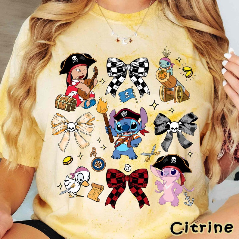 Może przedstawiać: Ż&oacute;łta koszulka tie-dye z r&oacute;żnymi postaciami pirat&oacute;w z kresk&oacute;wek i kokardami z motywem czaszki. Projekt zawiera piracką dziewczynę grającą na gitarze, Stitcha jako pirata i słowo "Citrine" na dole.