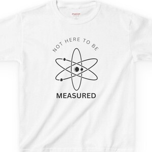 May include: White t-shirt with a black atom graphic and the text "Not here to be measured".