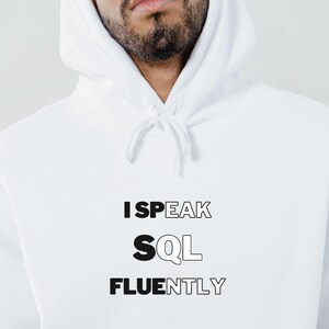 Op de afbeelding: Witte hoodie met zwarte tekst die "I SPEAK SQL FLUENTLY" zegt.