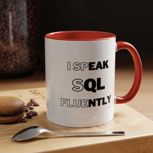 Puede incluir: Taza de cerámica blanca con borde y asa rojos. La taza tiene texto negro que dice "Hablo SQL con fluidez".