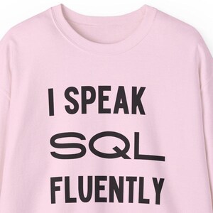 May include: A pink long-sleeved sweatshirt with the text "I SPEAK SQL FLUENTLY" printed in black.