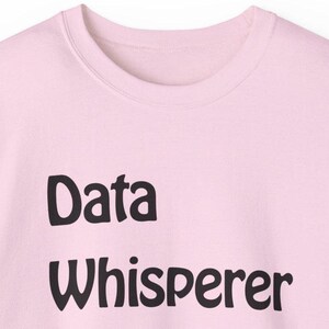 May include: A pink sweatshirt with the text "Data Whisperer" printed in black.