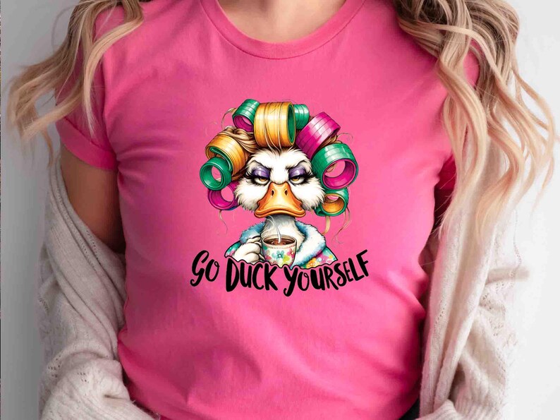 May include: Pink t-shirt featuring a cartoon duck with curlers, holding a coffee cup. The duck has an angry expression and the text "Go Duck Yourself" is below the image. The shirt is a solid pink color.