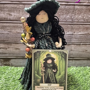 May include: A handmade doll of a witch named Ivy, wearing a black hat and green dress. The doll holds a staff with decorative elements. A card with the name "Ivy" and text about her personality and gift is in front of the doll.